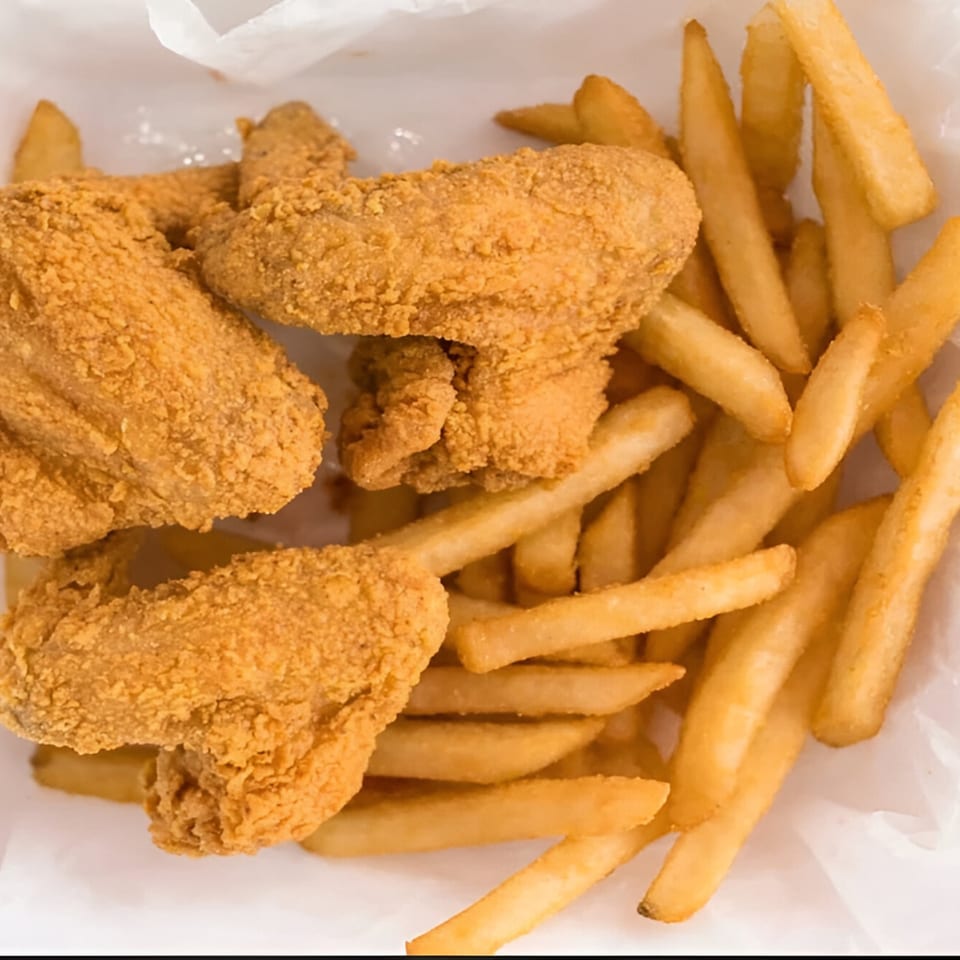 Golden-brown fried chicken pieces and french fries served in a white paper container from Sunrise Fish And Chicken.